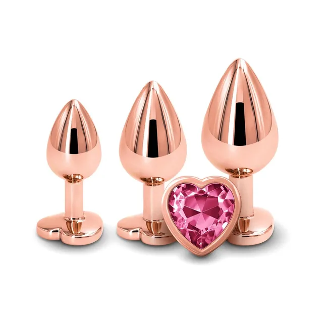 Three rose-gold metal plugs standing behind pink heart-shaped jewel base