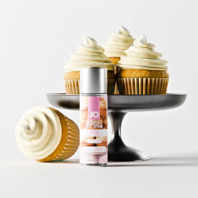 System JO frosted cupcake water-based lube 2 oz bottle arranged beside frosted cupcakes