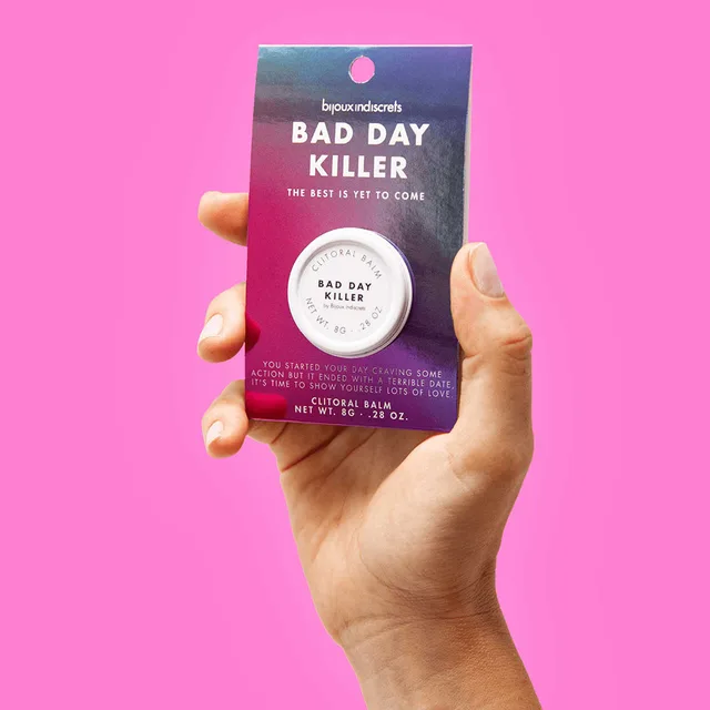 hand holding packaged Bad Day Killer balm against a bright pink background