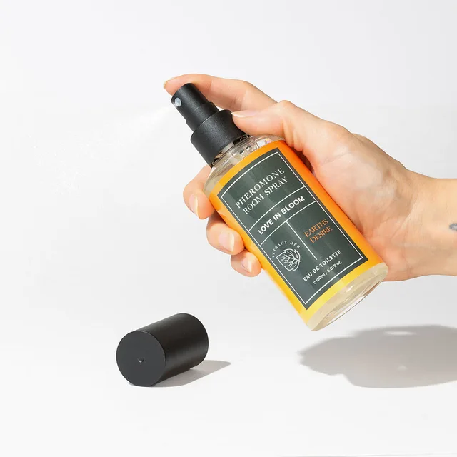 hand pressing the black pump on an Earth’s Desire room spray bottle