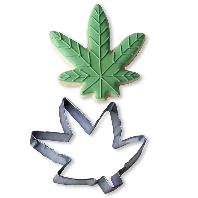 silver cannabis leaf cookie cutter beside green leaf-shaped cookie
