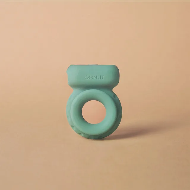 aqua OhNut vibrating ring with circular opening and rectangular motor pod on beige background