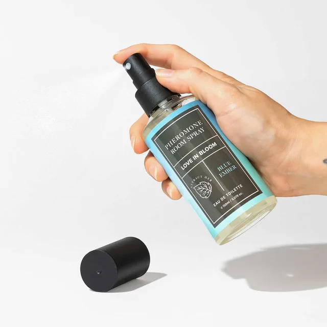hand pressing the black pump on a blue Blue Ember room spray bottle