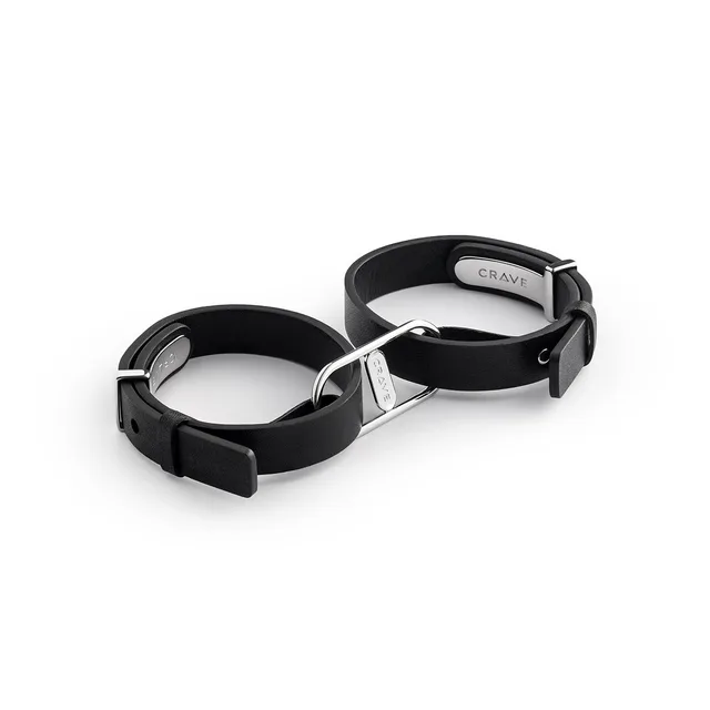 pair of black leather Crave cuffs linked by silver steel D-rings