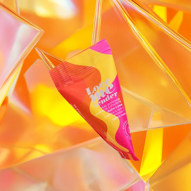 Love to Love Cotton Candy massage oil sachet angled packet among orange geometric shapes