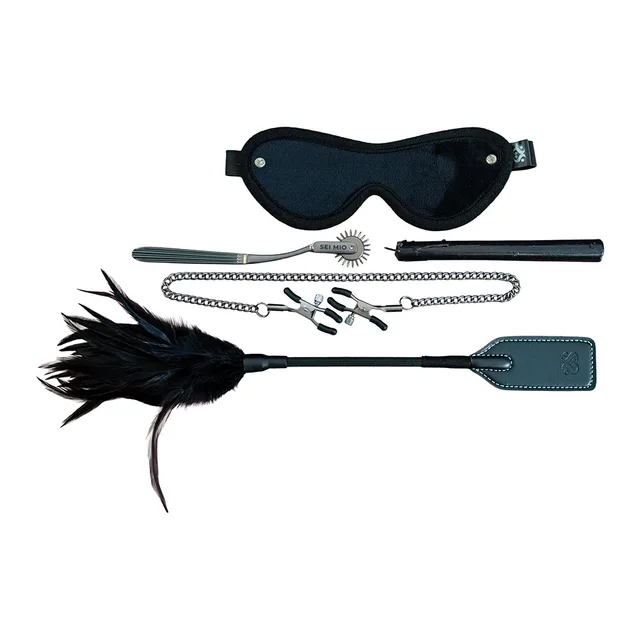 Black blindfold, feather tickler, paddle, clamps and slim tool arranged together