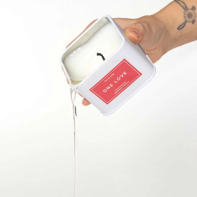 white Eye of Love One Love candle with red label and melted wax pouring