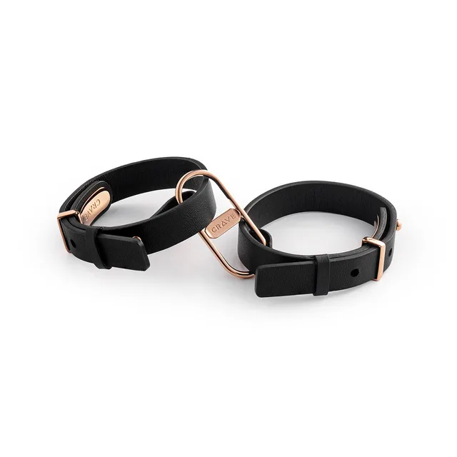 pair of black leather Crave cuffs linked by rose gold D-rings