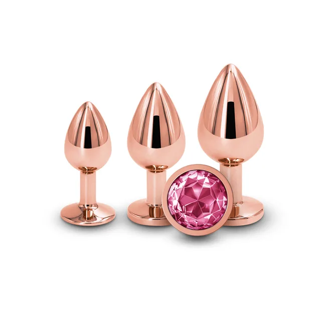 Three rose-gold plugs with round pink jeweled bases
