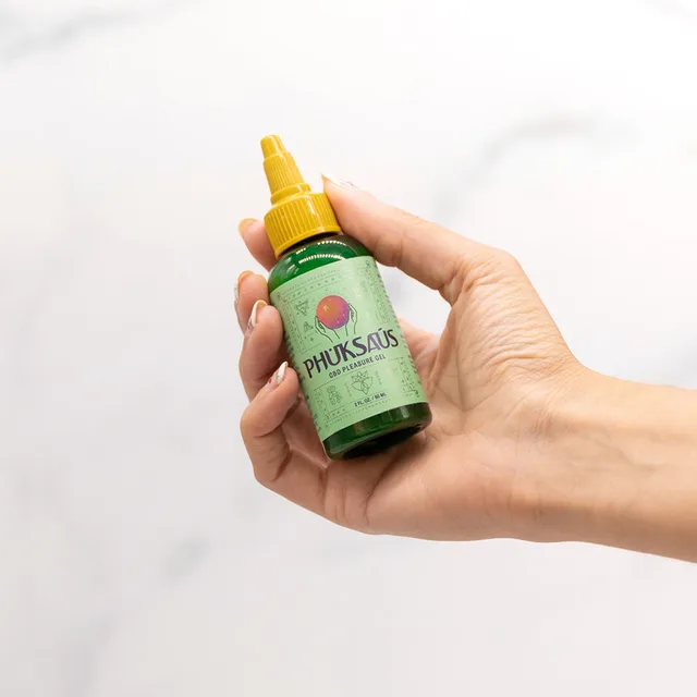 hand holding green 2 oz Phuksaus bottle against white background