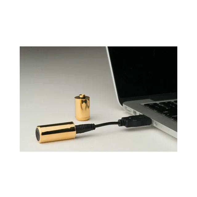 gold Crave Bullet connected by charging cable beside a laptop