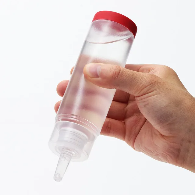 Clear Tenga Lotion bottle held upside down with red cap