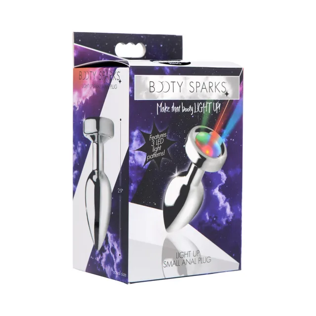 small silver Booty Sparks light-up anal plug with glowing multicolor cap on box