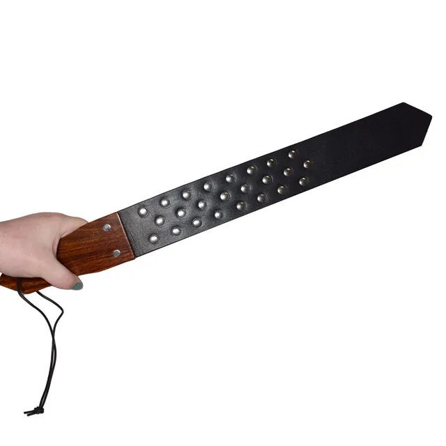 Hand holding Prowler RED studded paddle by brown wood handle