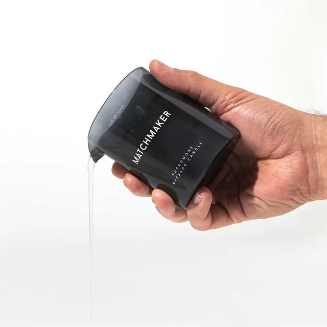 hand holding black Eye of Love Matchmaker massage candle jar