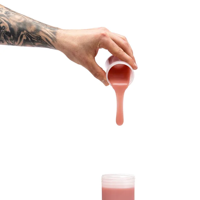 Hand pouring medium brown Clone-A-Willy silicone refill above open container