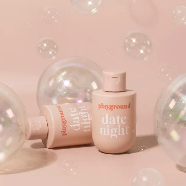 Playground Date Night 3.7 fl oz pink flip-top bottle among clear bubbles