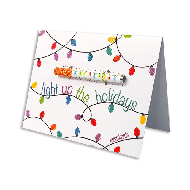 standing Light Up the Holidays KushKard with string lights and metal one-hitter