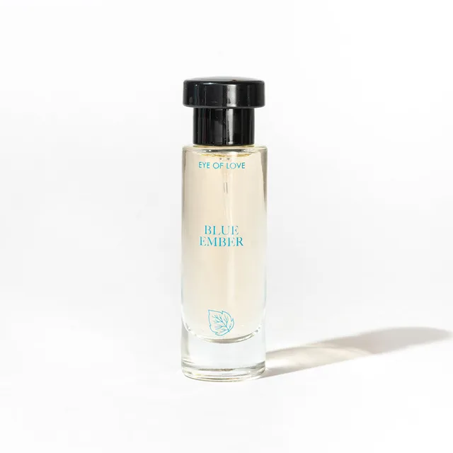 single Blue Ember glass parfum bottle with black cap casting a shadow on white