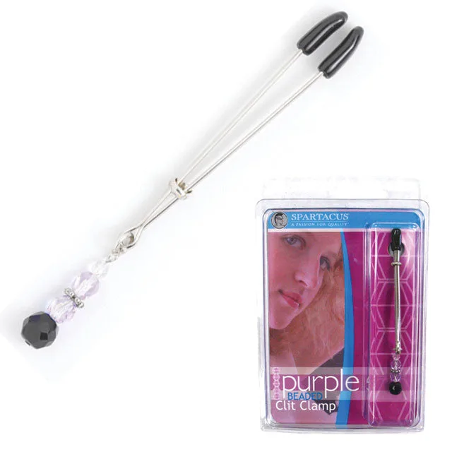 Silver Spartacus tweezer clit clamp with black tips and faceted purple bead beside its case