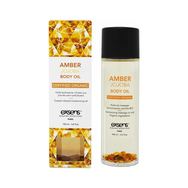 clear Exsens Amber Jojoba oil bottle with amber crystals beside gold carton