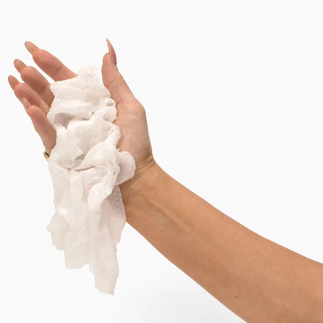 Hand holding a bundle of expanded white Beloved cleansing cloths