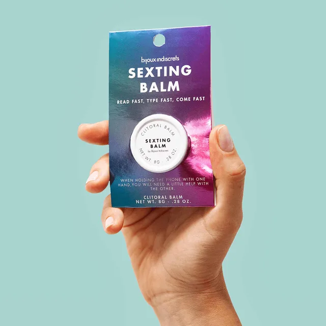 hand holding packaged Sexting Balm against a pale aqua background