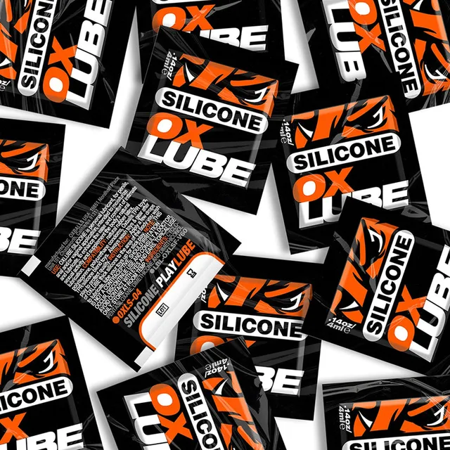 scattered black and orange Oxballs Silicone OXLube singlet packets