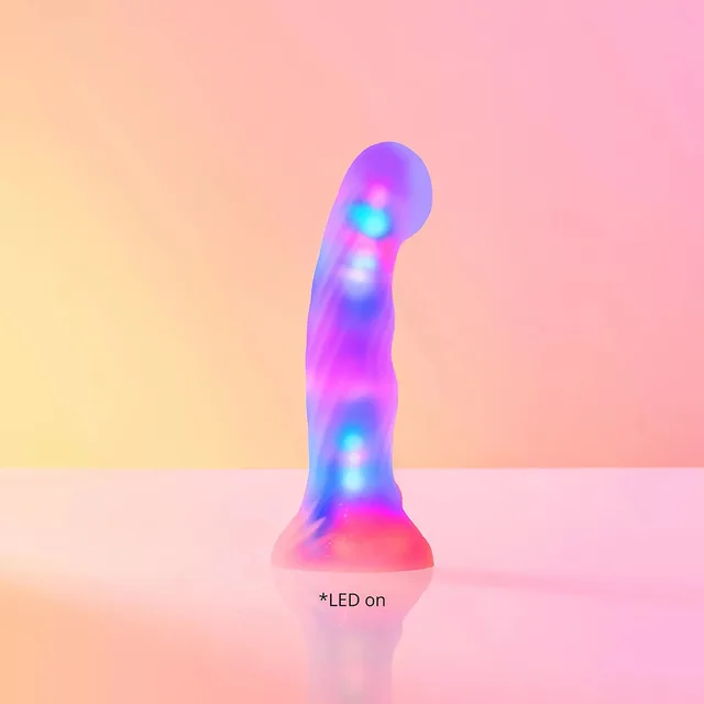 Lovely Planet Sugar Bomb LED silicone dildo yellow-and-pink curved dildo illuminated on a pastel surface