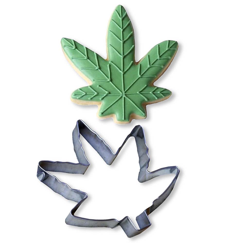 Cannabis Cookie Cutter silver cannabis leaf cookie cutter beside green leaf-shaped cookie