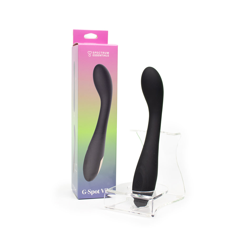 Spectrum Essentials Rechargeable Silicone G-Spot Vibrator Black Spectrum Essentials black rechargeable G-spot vibrator displayed beside its gradient retail box and clear stand