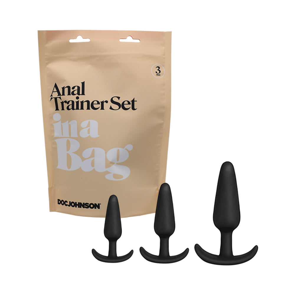 Doc Johnson Anal Plug Trainer Set In A Bag 3-Piece Silicone Black Three black silicone trainer plugs beside kraft In a Bag pouch
