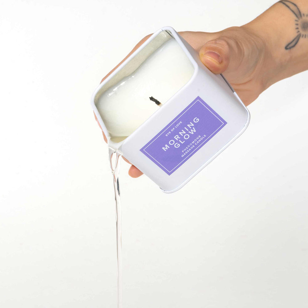 Eye of Love Morning Glow Attract Him Pheromone Massage Candle white Morning Glow square candle with purple label and melted wax pouring