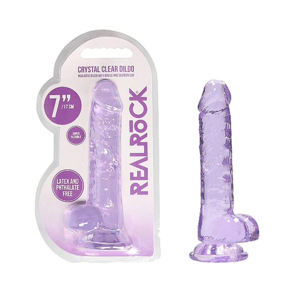 RealRock Crystal Clear Realistic 7 in. Dildo With Balls and Suction Cup Purple Purple RealRock Crystal Clear 7-inch dildo beside retail pack