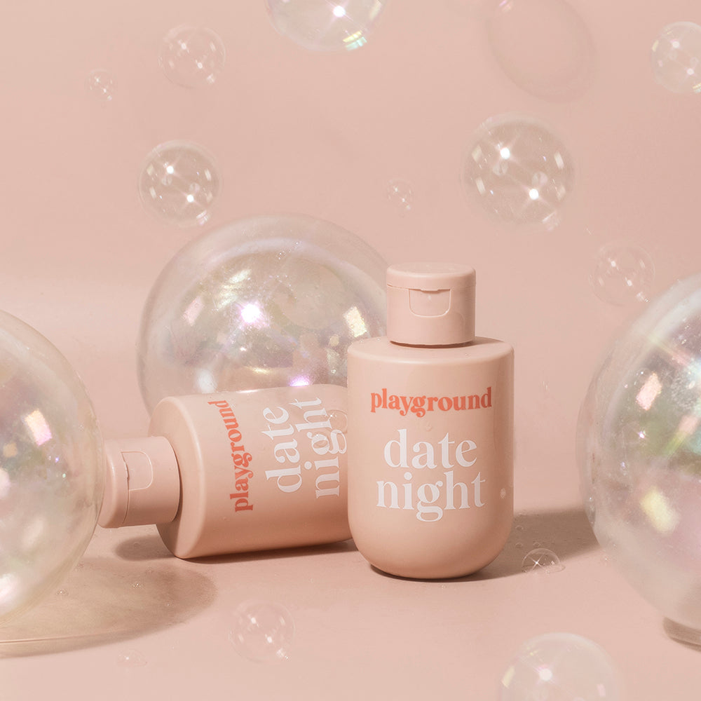 Playground Date Night Water-Based Personal Lubricant Playground Date Night 3.7 fl oz pink flip-top bottle among clear bubbles