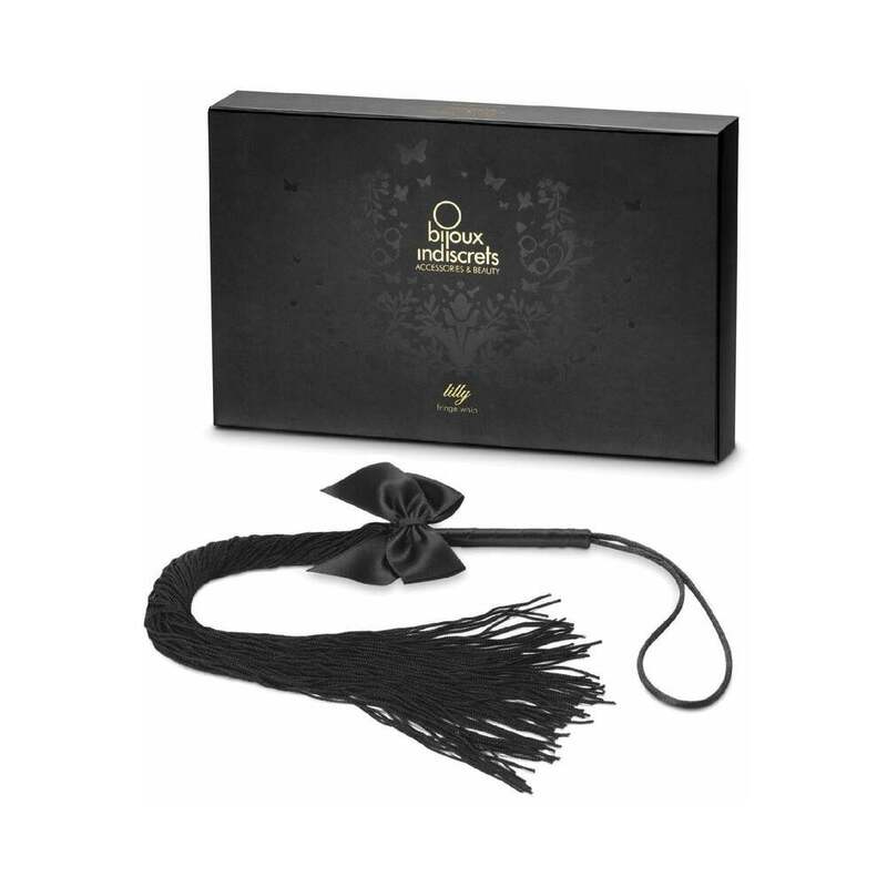 Bijoux Indiscrets Lilly Fringe Whip black Lilly fringe whip with satin bow loop handle and long tassels beside presentation box
